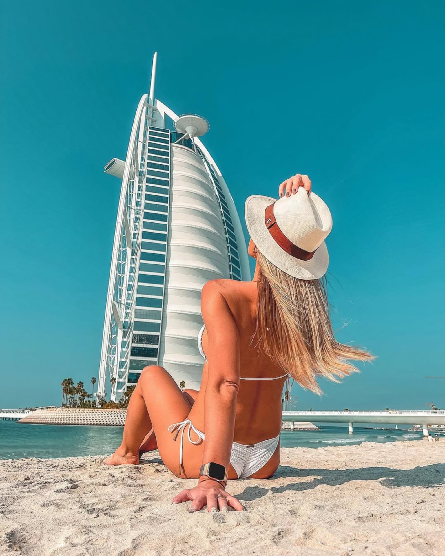 Emilim de chapéu na praia diante do Burj Al Arab, em Dubai