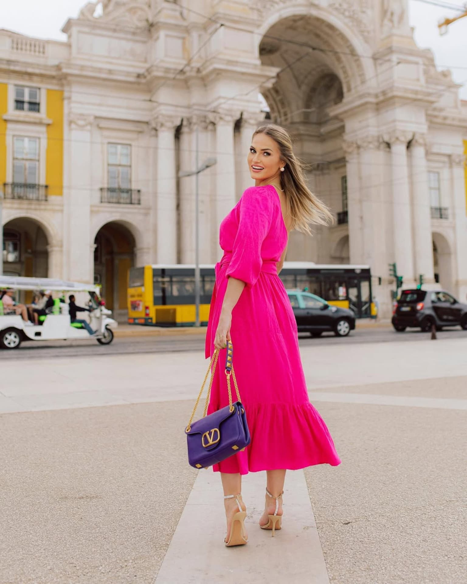 Emilim de vestido rosa na Praça do Comércio, com o Arco da Rua Augusta ao fundo, em Lisboa