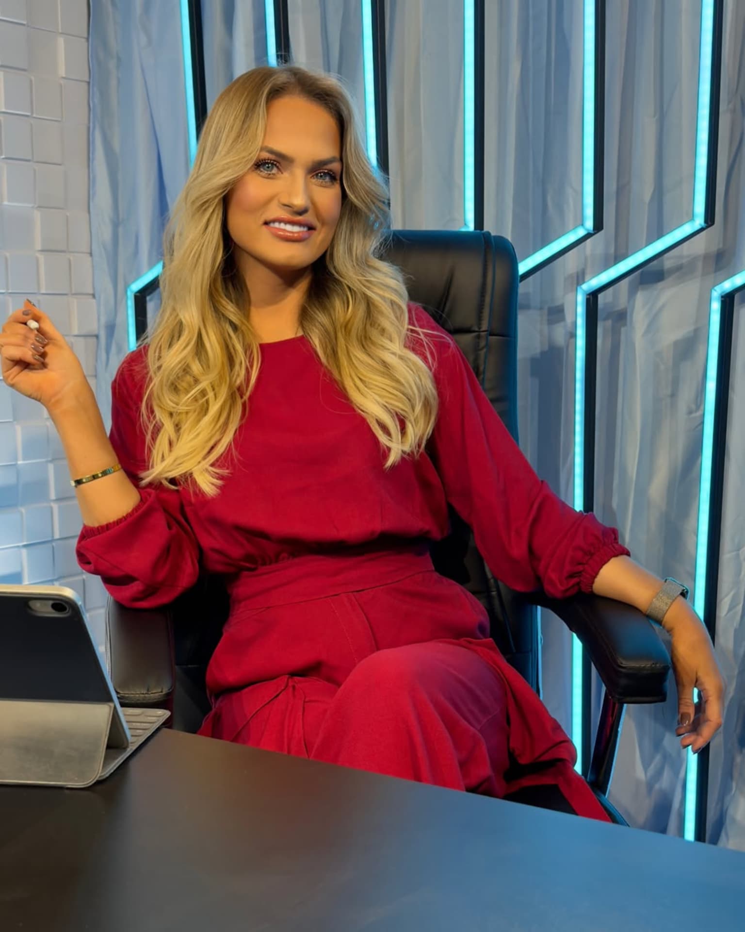Emilim no estúdio, de vermelho, com a caneta na mão