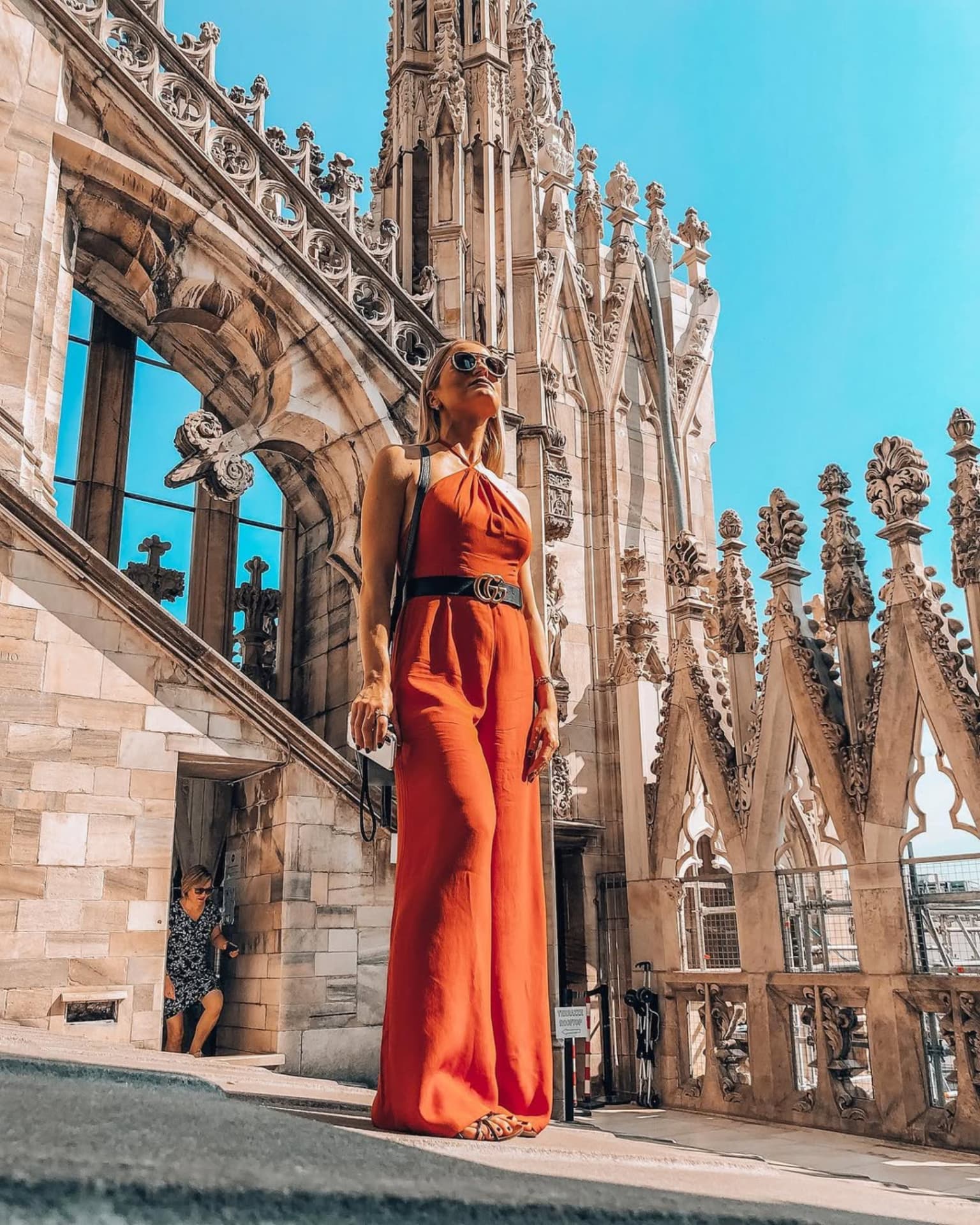 Emilim de macacão vermelho entre as esculturas e torres do Duomo de Milão